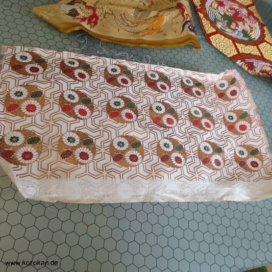 goldene Blütenkreise auf weißem Gitterbrokat