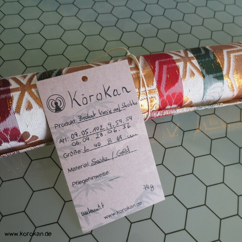 goldene Blütenkreise auf weißem Gitterbrokat